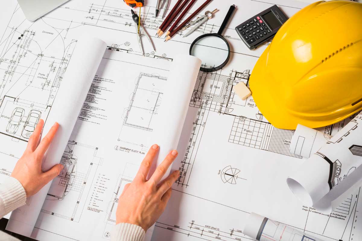 Fotografía de una mesa con un plano y diferente material como un casco de trabajar en la construcción...